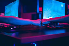 专业游戏玩家带耳机玩网络游戏锦标赛pc电脑，模糊的红色和蓝色背景