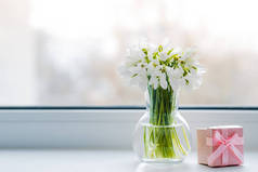 在春日的阳光下，美丽的玻璃雪花缀在窗台上，窗台上挂着一个粉色礼品盒。概念问候从三月八日母亲节，春天。自由空间，背景