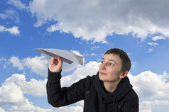 年轻的白人女孩开始纸飞机在湛蓝的天空