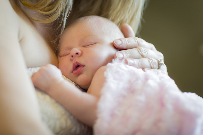 母亲抱着她刚出生的婴儿的女孩的手