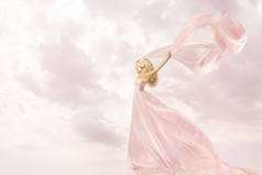幸福的女人，在粉红色的长礼服，丝绸围巾布飞越天空的女孩