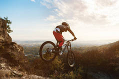 一个年轻的骑手在他的山地自行车的车轮在秋季森林下山的跳板上跳跃的伎俩