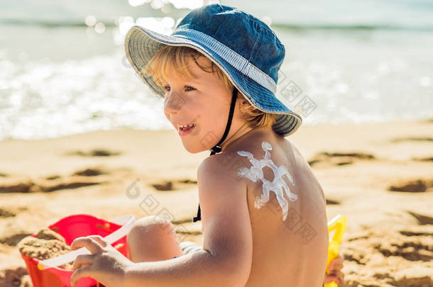 太阳用<strong>防晒</strong>霜, 婴儿背上晒黑乳液。白种小孩正坐在阳光明媚的海滩上, 有<strong>防晒</strong>霜和玩具的塑料容器。关闭, 室外.