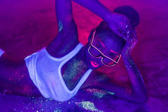性感的女人与萤光化妆在水泥地板上的身体和脸, 创造性的妆容看起来很适合夜总会。万圣节晚会, 表演和音乐概念