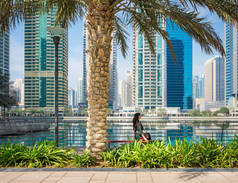 迪拜的朱美拉湖塔下坐在棕榈树下的女孩
