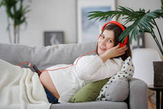 躺在沙发上的孕妇的形象, 听音乐的耳机