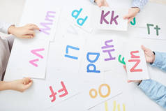 孩子们手中拿着带彩色字母的纸卡在字母游戏中