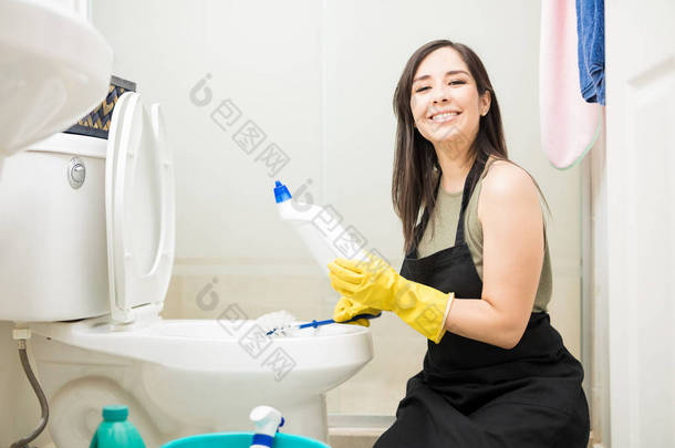 可爱的女服务员清洁酒店<strong>卫生间卫生间</strong>的洗手间与消毒剂和刷子