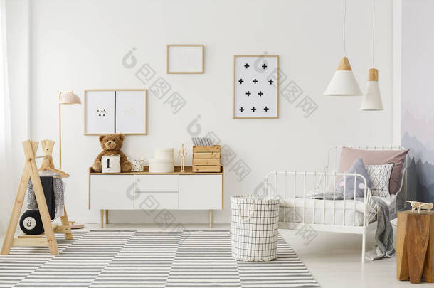 自然, 明亮的孩子的卧室内部与木制家具, 设计师配件和海报在白色的墙上