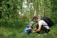 一个带着背包的男人, 父亲和儿子徒步旅行, 在树林里散步。家庭生活, 与家庭的消遣, 养育孩子.