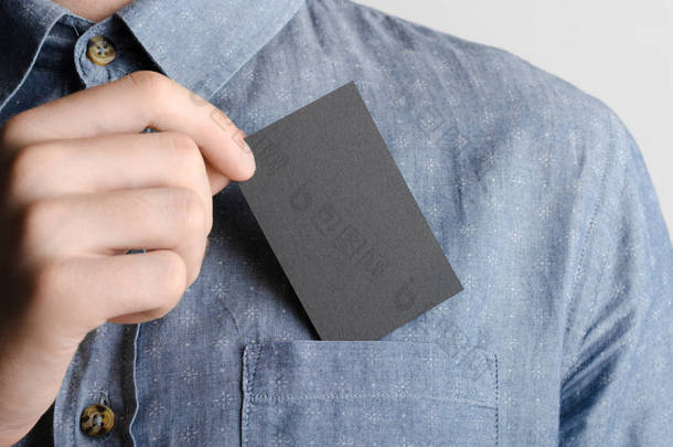 <strong>黑色名片</strong>模拟 (85x55mm)-男子在花格子布衬衫持有<strong>黑色</strong>卡的灰色背景.