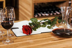 葡萄酒贮藏木桌上用笔记本和红玫瑰的红酒酒瓶特写镜头
