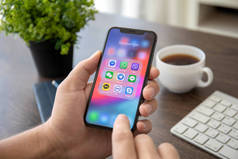 Alushta, 俄罗斯-2018年7月30日: 手持 iphone X 与社交网络信使在屏幕上的人手。iphone 10 是由苹果公司创建和开发的。.