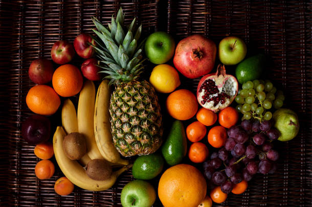 大量的水果采摘在明亮的复合水果躺在一个黑暗的柳条桌上, 每天维生素充电最美味和健康的水果