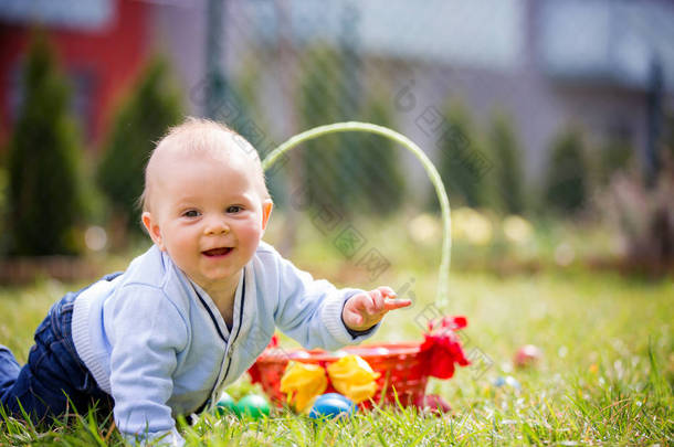 可爱的小男孩在复活节的春天公园狩猎复活节彩蛋。可爱的小宝宝与可爱的可爱的兔子庆祝盛宴户外