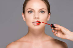 化妆师的部分观点应用红唇膏对模型嘴唇孤立的灰色