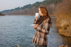 在户外喝一杯的浪漫女孩。嬉皮士姑娘在春天的山水里喝茶