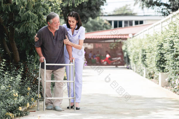 <strong>护士</strong>与病人使用沃克在退休回家。年轻的女<strong>护士</strong>抱着老人的肩膀在户外花园散步。高级护理、护理人员和高级退休家庭服务概念.