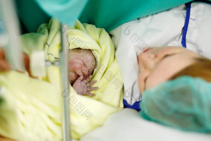 刚出生的婴儿在出生后包裹在毯子里寻找第一