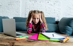 可爱的小学生感到悲伤和困惑, 而做困难的任务与她的笔记本电脑在家里。家庭作业与儿童教育理念.