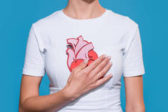 裁剪拍摄的妇女在白色 t恤与纸的心脏在蓝色的背景