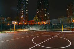 照明篮球场与红色路面, 现代新的篮球网和镜头耀斑的背景.