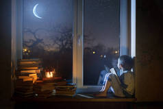 晚上, 孩子坐在窗台上看着星星和梦.