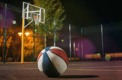 五颜六色篮球球与篮子和网在背景在黄昏红色领域与轻发光