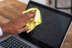 男子用黄布清洁手提电脑屏风的特写
