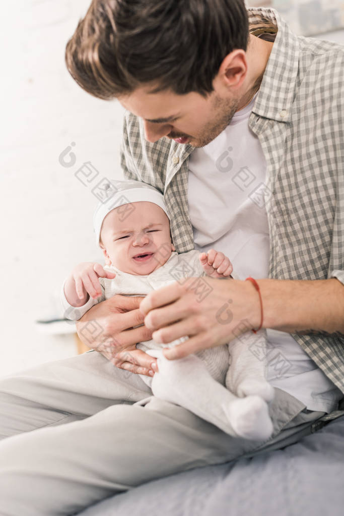 父亲手里抱着哭闹的婴儿的画像