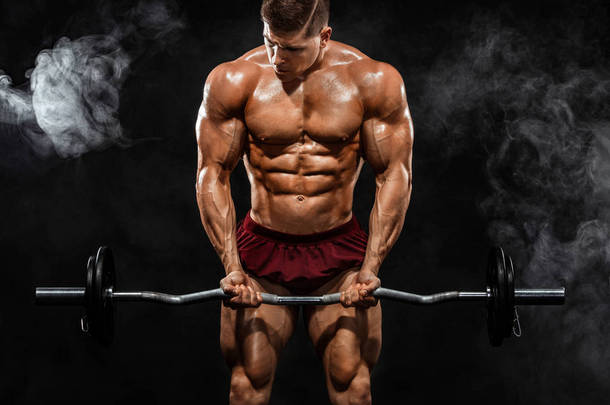 残酷强壮的肌肉健美运动的人在黑色的背景下, 用杠铃抽打肌肉。锻炼健美的概念。体育营养广告的复制空间.