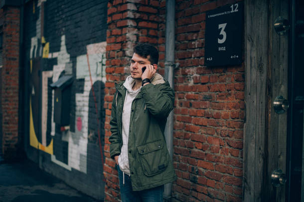一个人在城市景观的背景下通电话。工业景观中的年轻商人用手机进行交流
