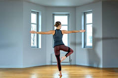 年轻的运动型女子练习瑜伽, 锻炼, 穿着运动服, 裤子和上衣, 室内关闭, 瑜伽工作室。后视图