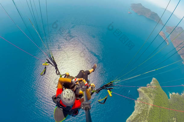 在天空中滑翔伞。在阳光明媚的日子里, 滑翔伞在海上与蓝色的水和山脉一起飞行。土耳其奥卢德尼兹滑翔伞和蓝色泻湖鸟图。极限运动。景观