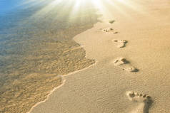 美丽的脚印在海边的沙滩上，在大自然的背沟