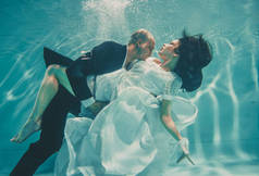 美丽的浪漫夫妇的新娘和新郎结婚后游泳轻轻地在水下和放松