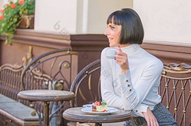 她喜欢甜食。女人迷人的优雅黑发吃美食蛋糕咖啡馆露台背景。愉快的时间和放松。美味的美味蛋糕。女孩放松咖啡馆与蛋糕甜点。美食理念