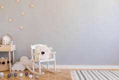 时尚的斯堪的纳维亚新生儿房，配有玩具、儿童椅、带泰迪熊的天然篮子和小搁板。现代内饰，灰色背景墙，木制镶木地板和星星图案.