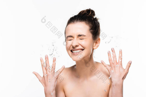 快乐赤裸裸的年轻黑发女人与自然之美洗涤与干净的水飞溅和手势孤立在白色