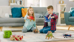 在客厅里：男孩和女孩玩玩具飞机和恐龙，而坐在地毯上。阳光明媚的客厅，孩子们玩得开心.