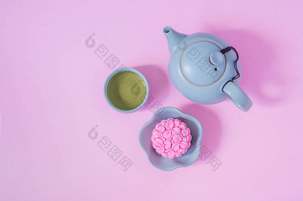 粉红月饼，蓝色茶壶，粉红色<strong>背景</strong>上的绿茶。中国<strong>中秋节</strong>食品.