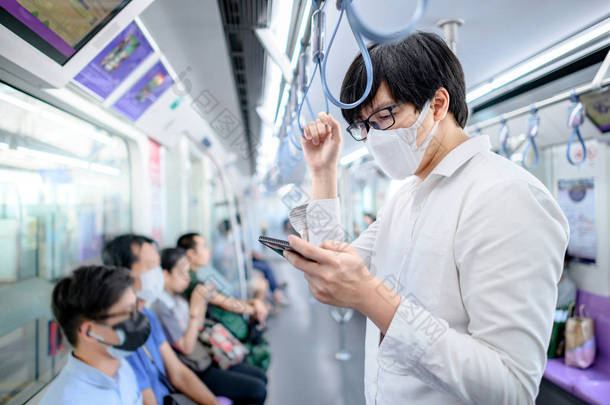亚洲人戴着外科口罩，在天桥或城市火车上使用智能手机。武汉市公共交通中的COVID-19禽<strong>流感</strong>疫情<strong>预防</strong>。对流行病保护的健康认识