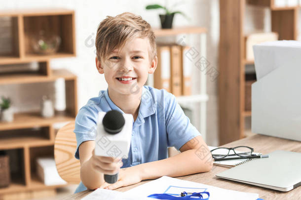 Little journalist with microphone having an interview in office