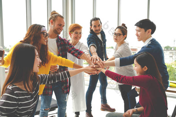 在现代办公室里，多种族的年轻团队以团结和团队精神携起手来。多样化的群体聚集在一起合作或朋友们聚在一起的概念。用柔和的语调建立创业团队.