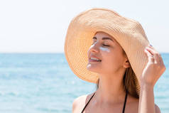美丽的女人在海滩用防晒霜保护她的皮肤.