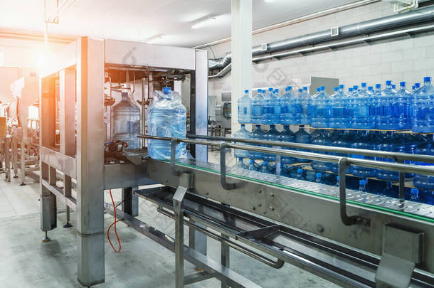 输送带、大蓝色瓶子或加仑中的水、饮料厂内部、工业生产生产线