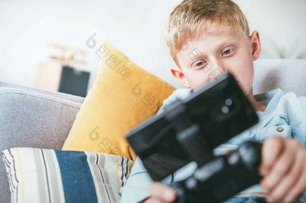 十几岁的男孩玩与游戏板连接的智能手机游戏