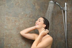 快乐的湿湿的女人在水里享受着淋浴，水头落在浴室里