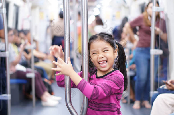 亚洲小孩或小女孩笑着享受乘坐<strong>地铁</strong>或<strong>地铁</strong>的天空火车或电动车，并在假日乘坐火车在城市街道上享受愉快的旅行或交通乐趣