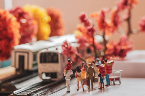 秋季或秋季在月台上等待或挥动列车的团体过路人的微型玩具雕像- -采用暖色调过滤器.